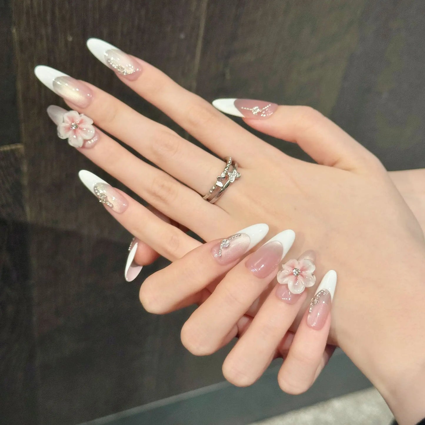 Manicura francesa de ojo de gato con diseño floral 3D, hecha a mano y que resalta la piel clara.