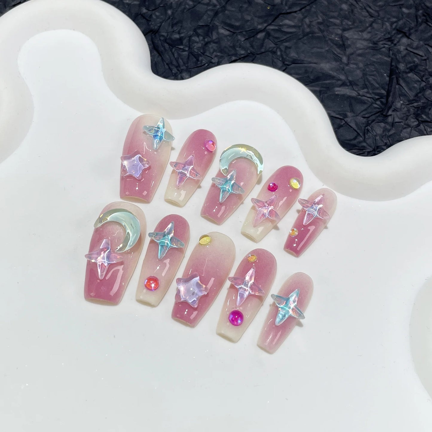 Nuevas pegatinas para uñas de longitud media hechas a mano con diseño de cielo estrellado color moca y uñas acrílicas en tono morado ruborizado.