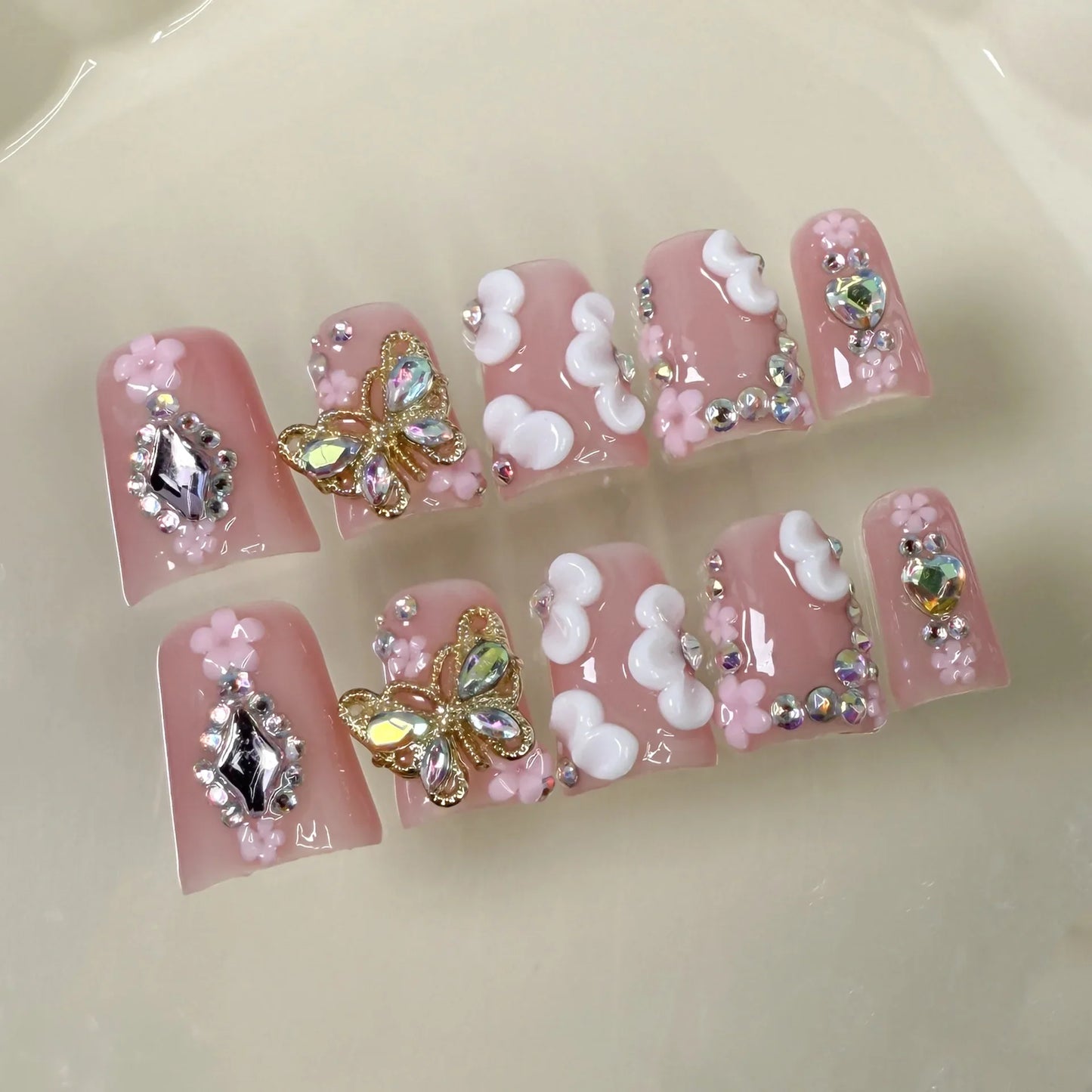 10 uñas postizas cortas rosas con diseño de pico de pato, frescas y dulces, hechas a mano con flores blancas 3D, de metal dorado y decoración de mariposas.