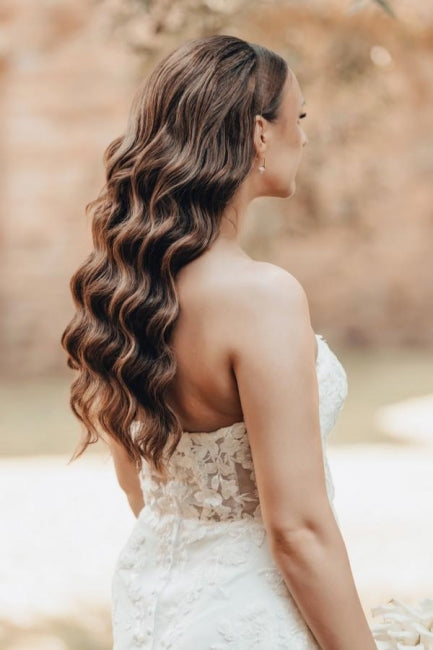 Vestido de novia largo color marfil con cola, estilo sirena, sin tirantes y encaje.