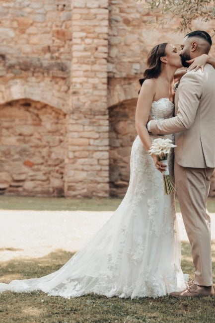 Vestido de novia largo color marfil con cola, estilo sirena, sin tirantes y encaje.