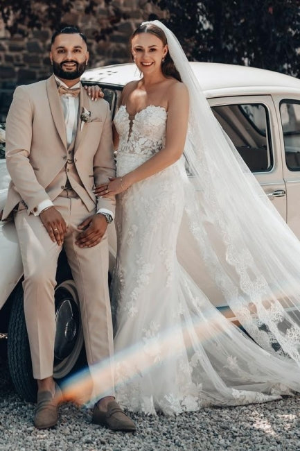 Vestido de novia largo color marfil con cola, estilo sirena, sin tirantes y encaje.