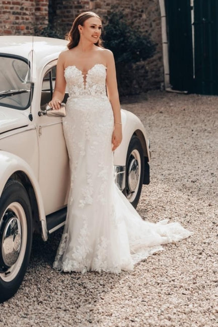 Vestido de novia largo color marfil con cola, estilo sirena, sin tirantes y encaje.