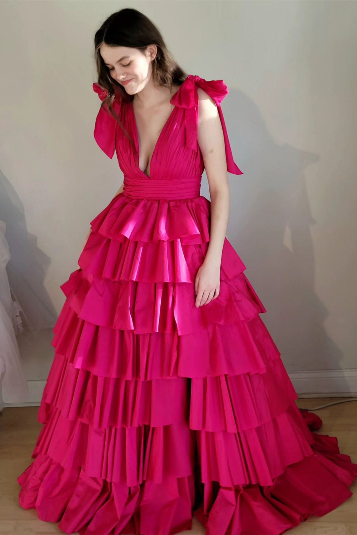Vestido de gala fucsia con escote en V pronunciado, tirantes con lazo y volantes