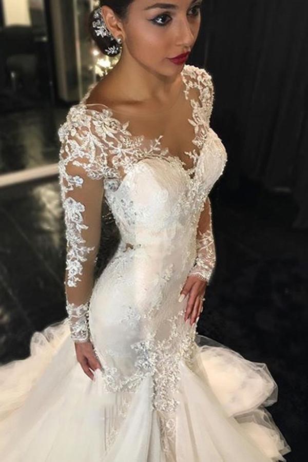 Vestido de novia color marfil con cola de corte y mangas largas y apliques de encaje