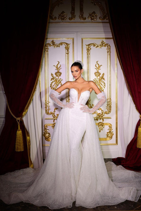 Lujoso vestido de novia largo color marfil con escote en V, corte sirena, sin mangas, con lentejuelas y cuentas, y cola desmontable.