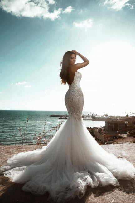 Impresionante vestido de novia de sirena con escote en forma de corazón y pedrería, sin mangas, de tul.