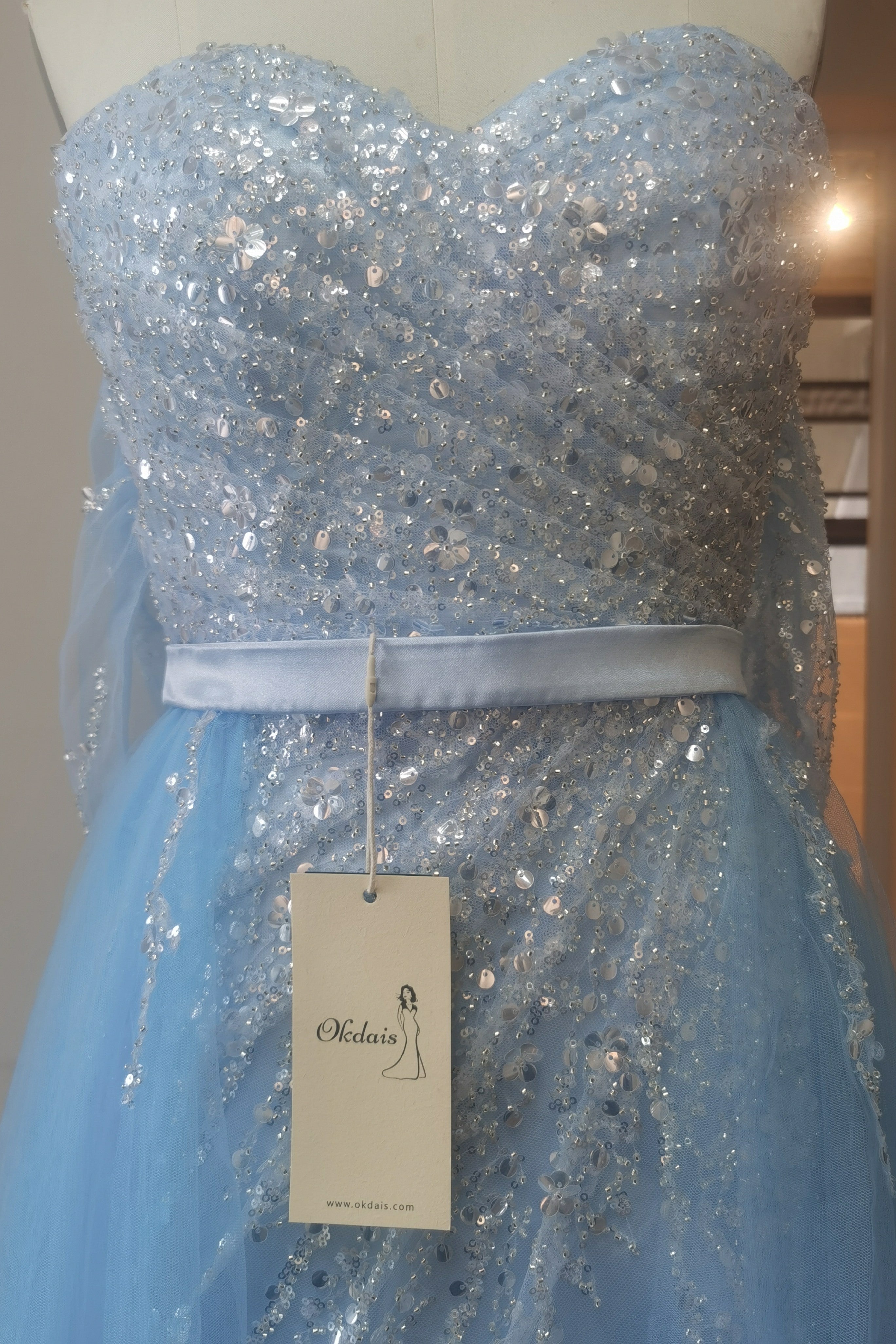 Vestido de baile azul céu claro com tule e decote ombro a ombro, com aplicações de lantejoulas dividido à frente