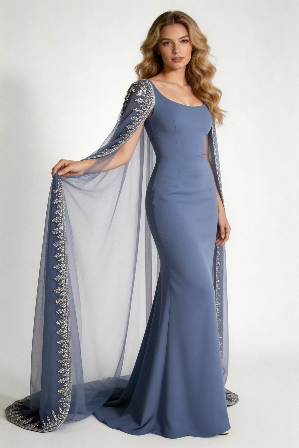 Woman wearing elegant blue embellished evening dress with cape, standing in modern living room