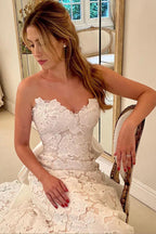 فستان زفاف عاجي بدون أكتاف بقصة على شكل حرف أ مزين بالدانتيل الزهري مع ربطة ساتان