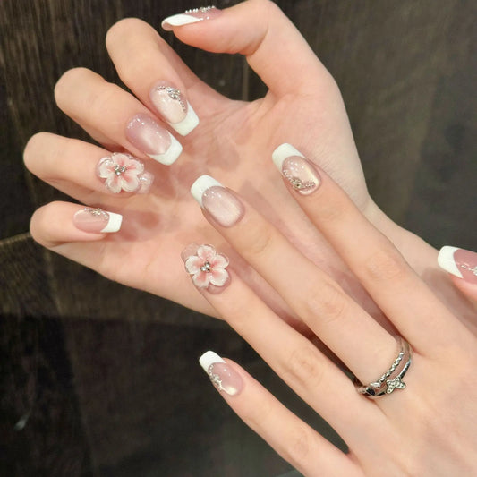 Manicura francesa de ojo de gato con diseño floral 3D, hecha a mano y que resalta la piel clara. 