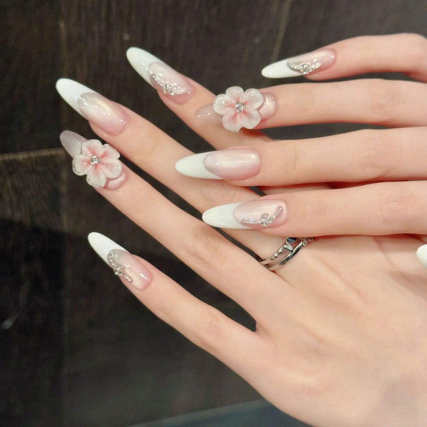 Manicura francesa de ojo de gato con diseño floral 3D, hecha a mano y que resalta la piel clara. 