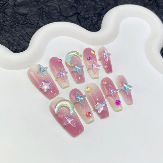 Nuevas pegatinas para uñas de longitud media hechas a mano con diseño de cielo estrellado color moca y uñas acrílicas en tono morado ruborizado. 