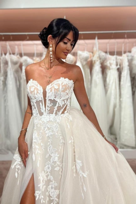 Abito da sposa incantevole senza maniche, lunghezza fino al pavimento, con scollo a cuore, gonna a trapezio divisa davanti, in tulle e pizzo con applicazioni