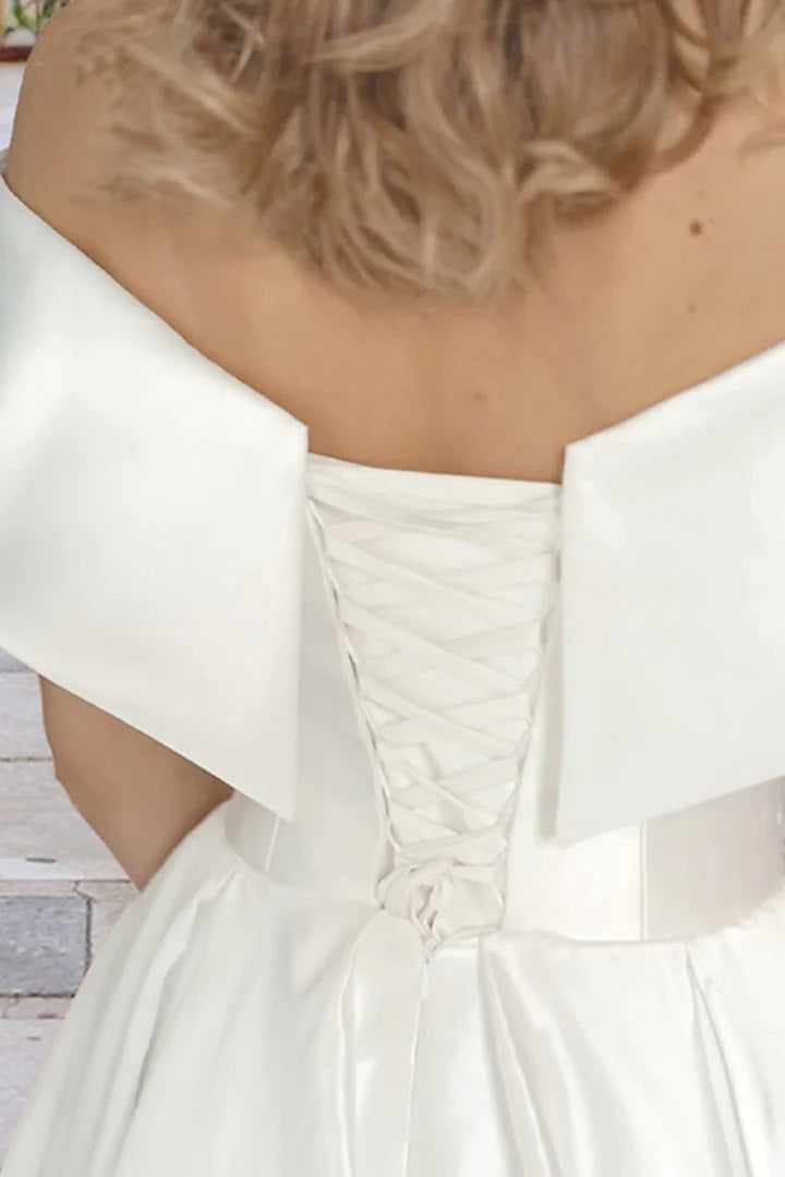 Vestido de novia playero de satén con hombros descubiertos y bolsillos, largo hasta la rodilla