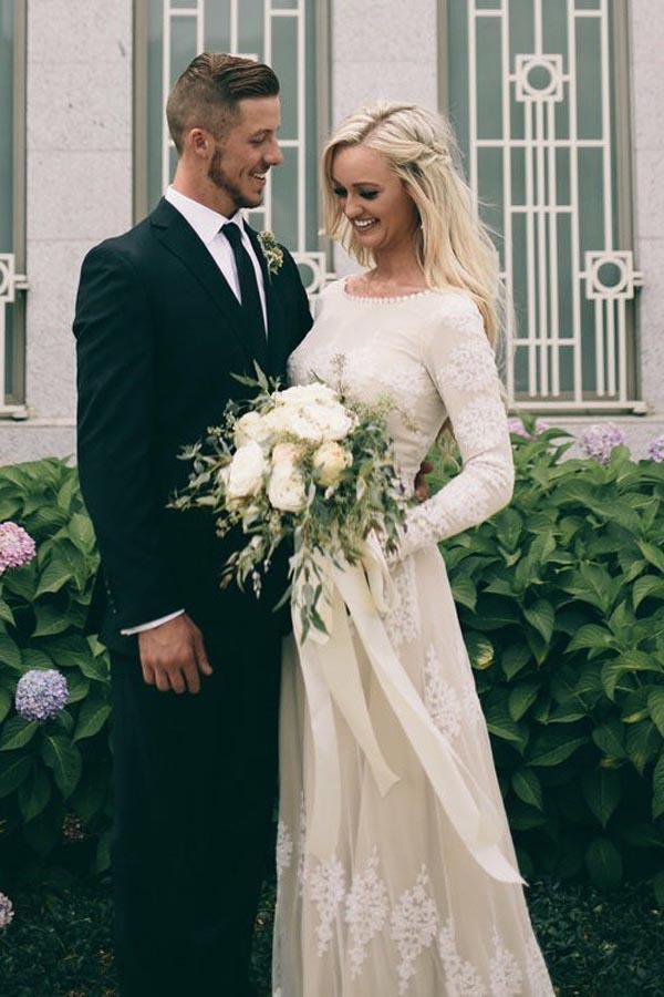 Vestido de novia de tul color marfil con mangas largas y corte barco y apliques