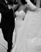 فستان زفاف أبيض طويل بأشرطة رفيعة من الدانتيل على شكل حورية البحر بدون أكمام مزين بالتطريزات