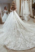 Belle robe de mariée princesse à encolure bardot, coupe évasée, ornée d'appliques, avec traîne
