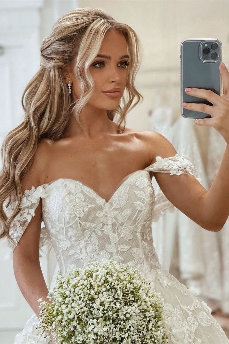 Belle robe de mariée princesse à encolure bardot, coupe évasée, ornée d'appliques, avec traîne