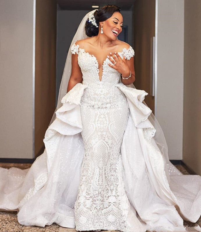 Abito da sposa lungo a sirena con maniche a cappuccio e sopragonna arricciata