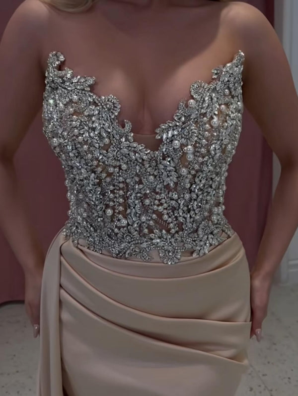 Abito da sera lungo color champagne con coda di sirena, senza spalline, ornato di gioielli raffinati