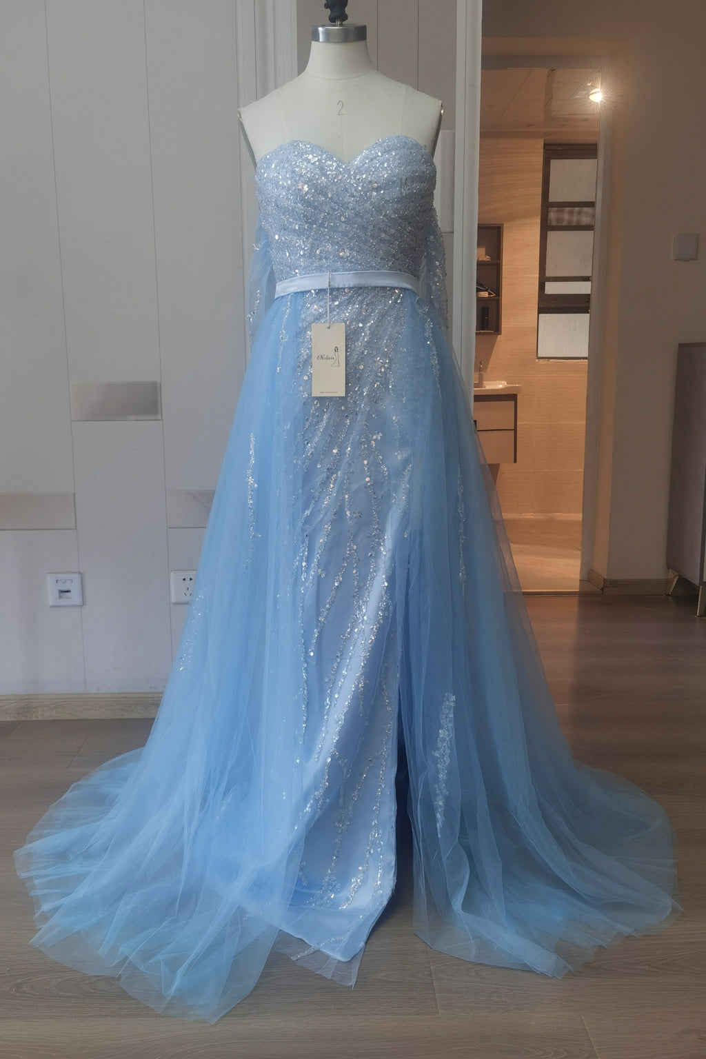 Vestido de baile azul céu claro com tule e decote ombro a ombro, com aplicações de lantejoulas dividido à frente