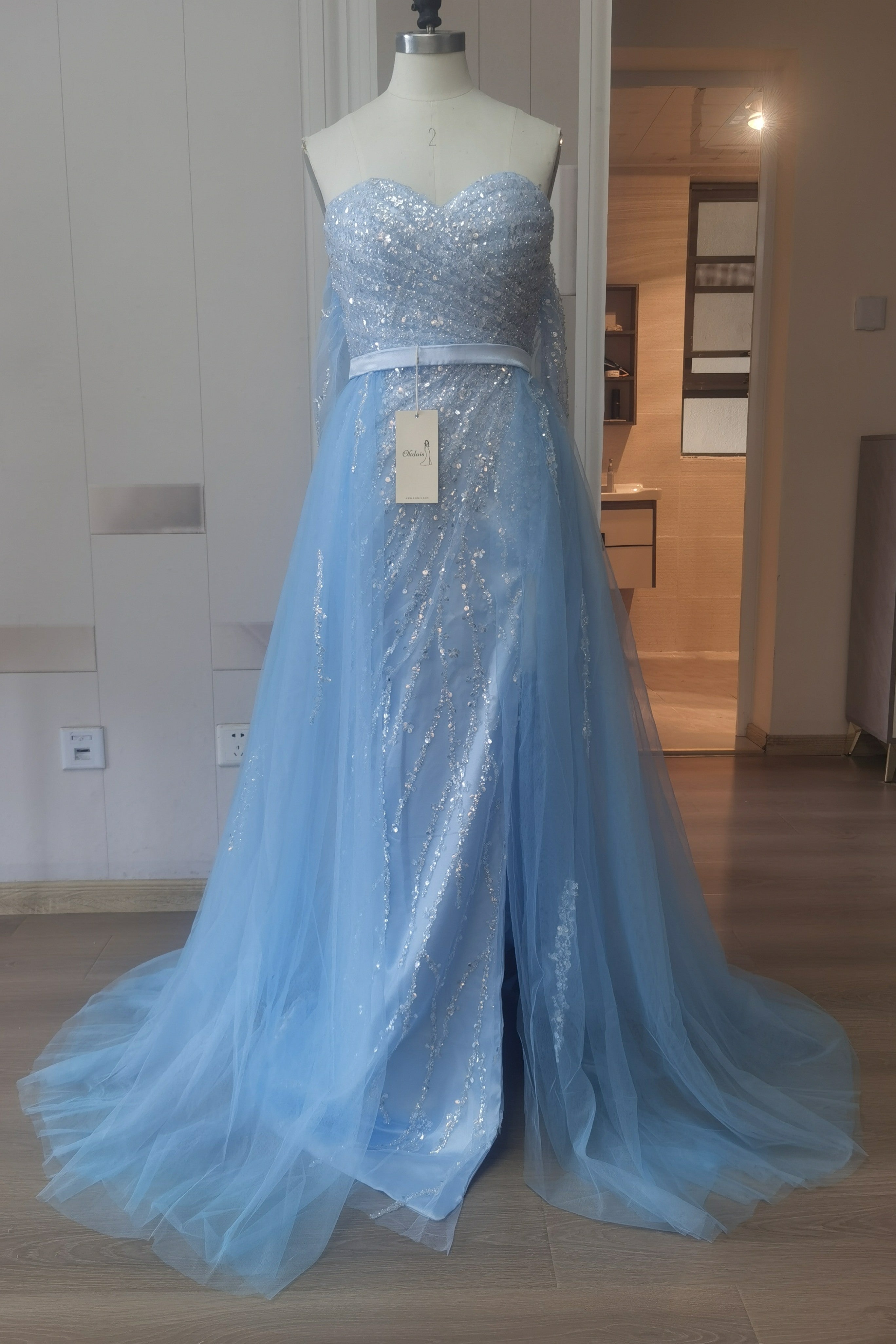 Abito da sera azzurro cielo con scollo a spalle scoperte e balze in tulle, decorato con paillettes
