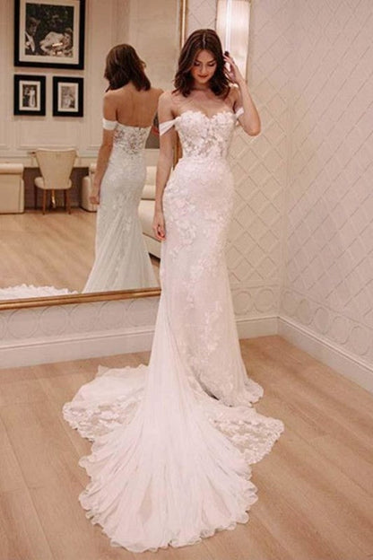 Vestido de novia elegante color marfil con apliques y hombros descubiertos, estilo playero y cola de corte.